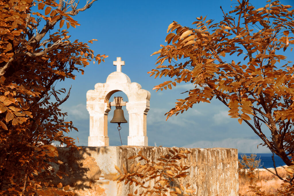 Medieval bellfry with bell surrounded by orange Autumn leaves in Rethymno city, Crete