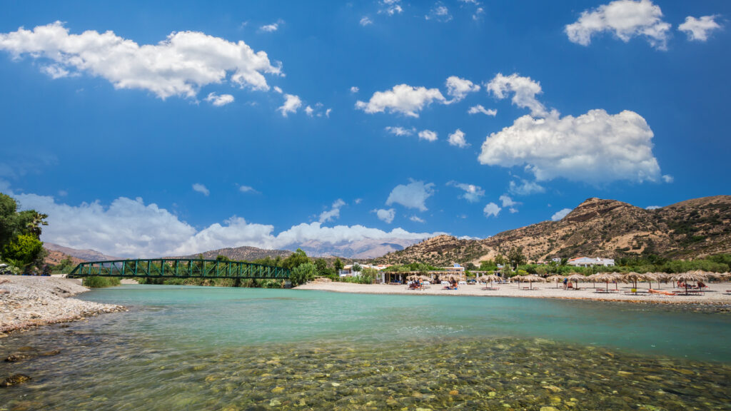 Tourists relax and bath in crystal clear water of Agia Galini Beach.